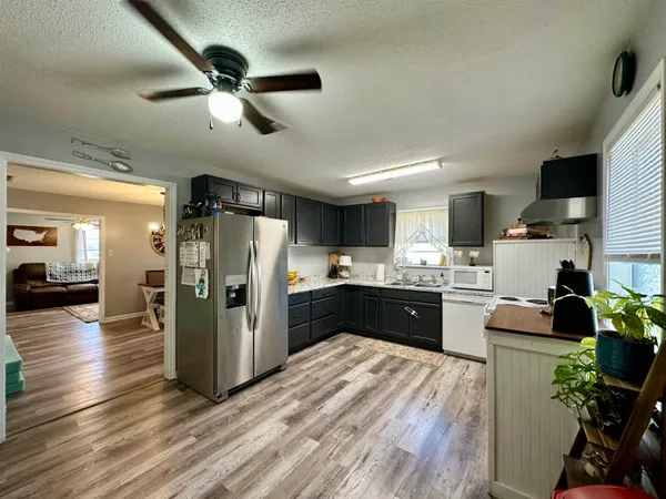 a kitchen with stainless steel appliances kitchen island granite countertop a refrigerator a sink dishwasher a stove and a dining table with wooden floor