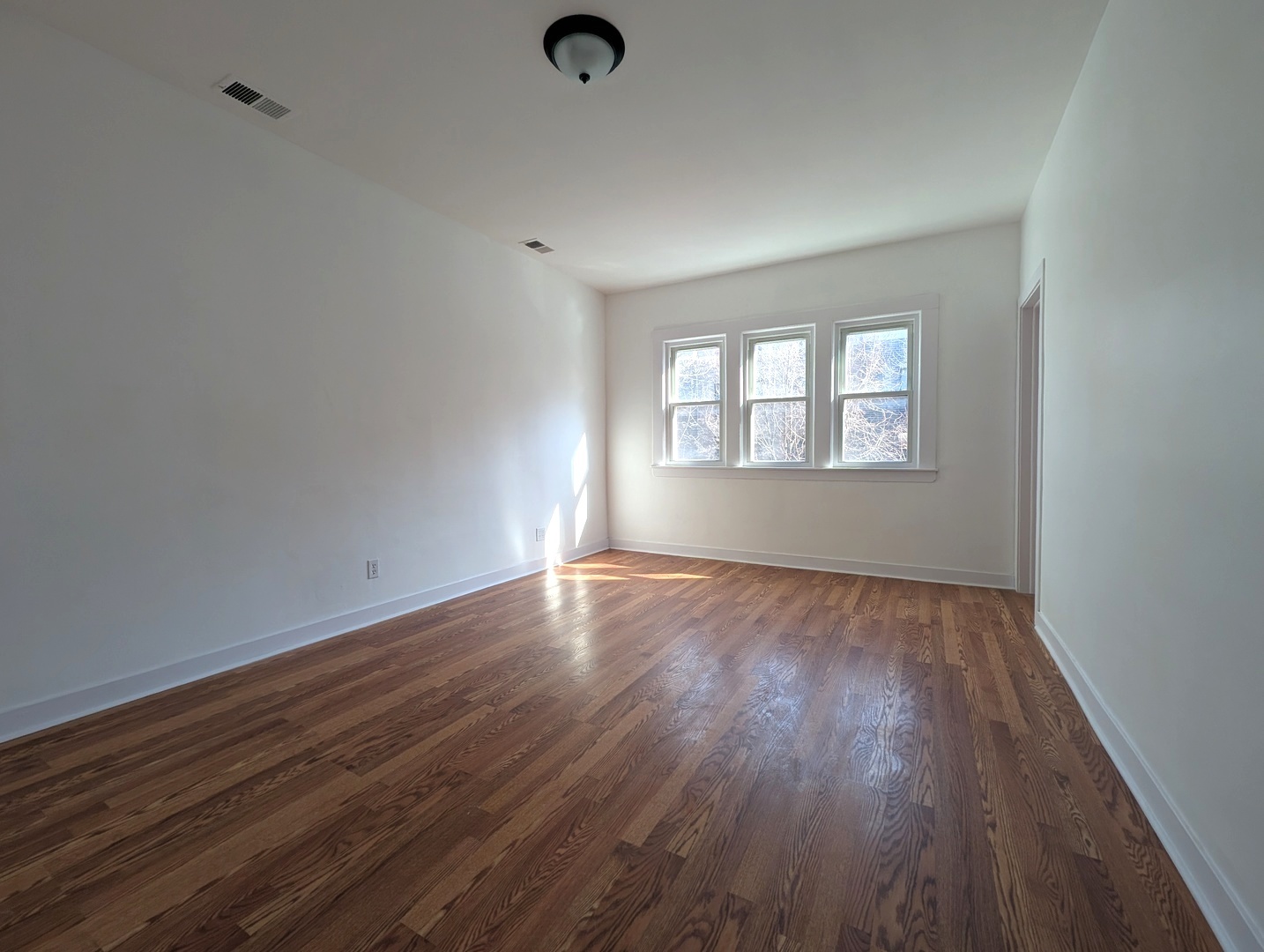 1520 West Melrose Street, Unit 2F Chicago, IL 60657 - Photo 2 of 16 an empty room with wooden floor and windows
