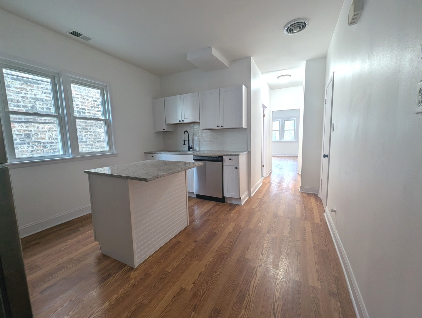 1520 West Melrose Street, Unit 2F Chicago, IL 60657 - Photo 4 of 16 a kitchen with stainless steel appliances granite countertop wooden floors and white walls