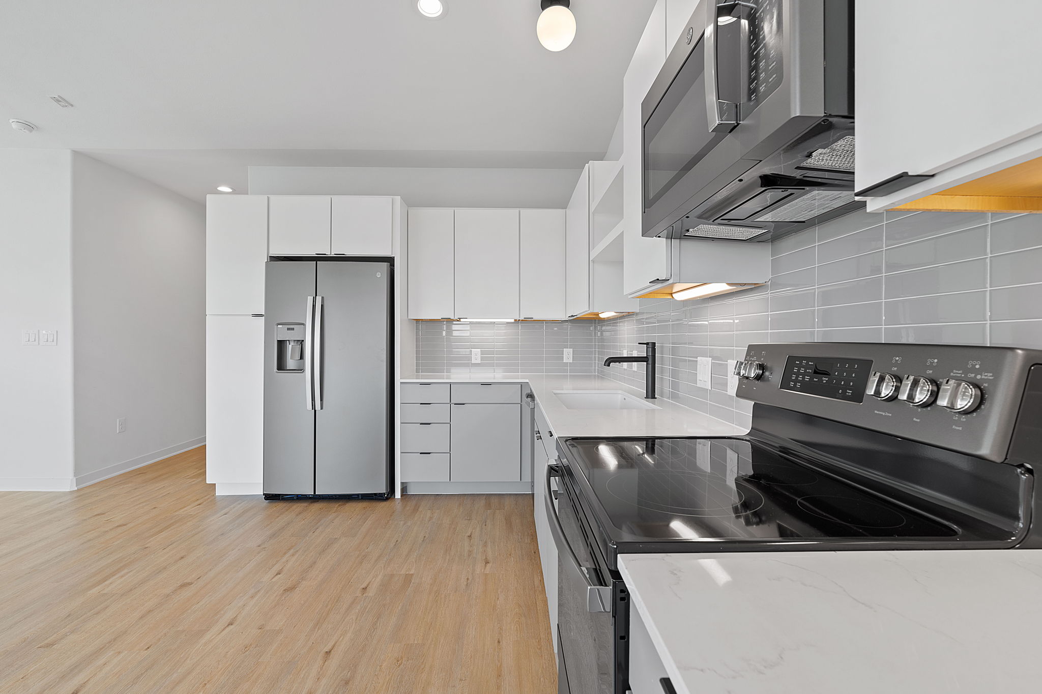 100 West Mockingbird Lane, Unit 307 Austin, TX 78745 - Photo 1 of 1 Kitchen featuring appliances with stainless steel finishes, light wood finished floors, decorative backsplash, white cabinetry, and modern cabinets