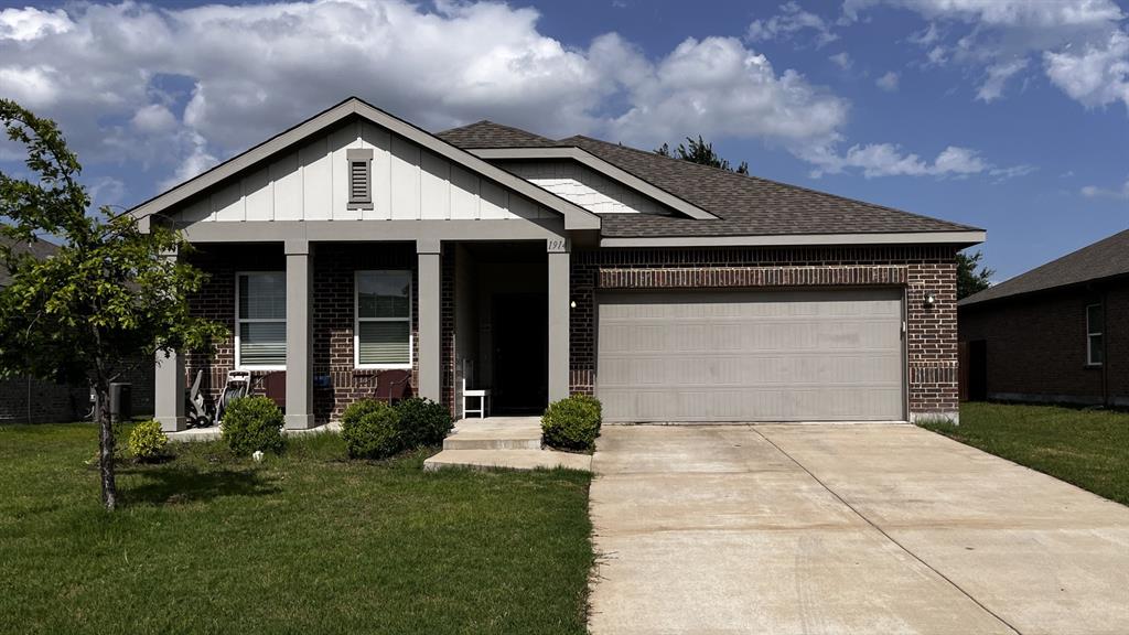View of front of house featuring brick siding, board and batten siding, a front lawn, concrete driveway, and a garage