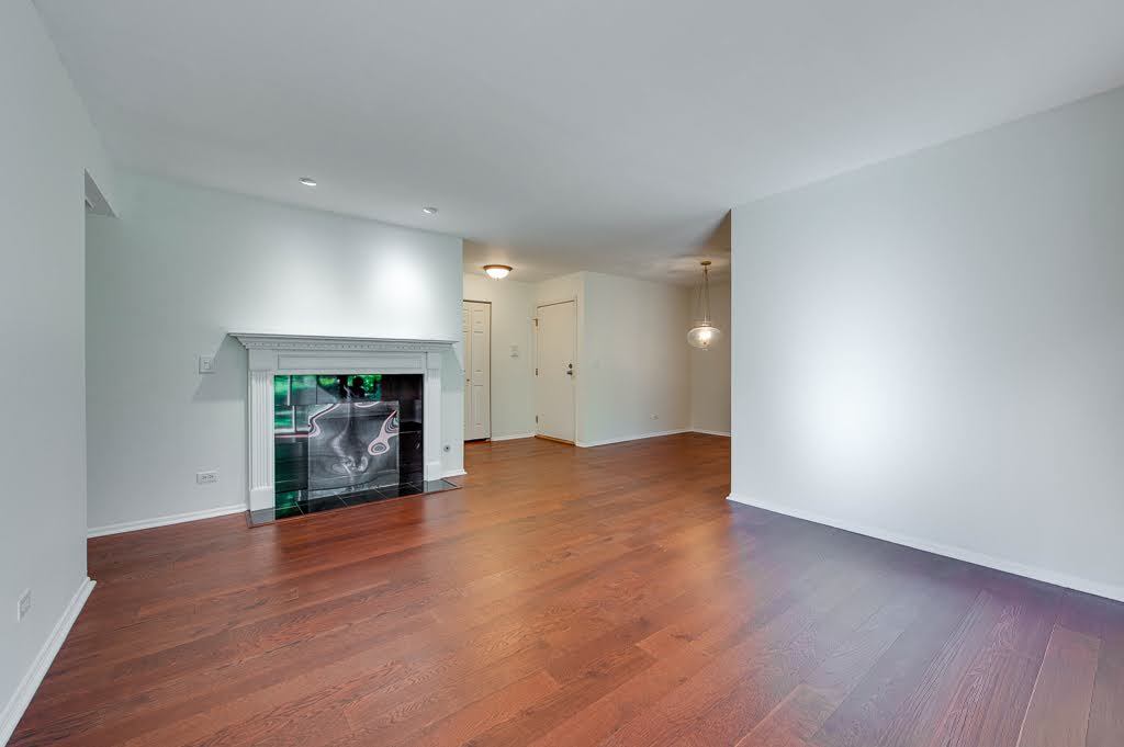 1251 Williamsburg Drive, Unit D1 Schaumburg, IL 60193 - Photo 7 of 26 a view of an empty room with wooden floor fireplace and a window