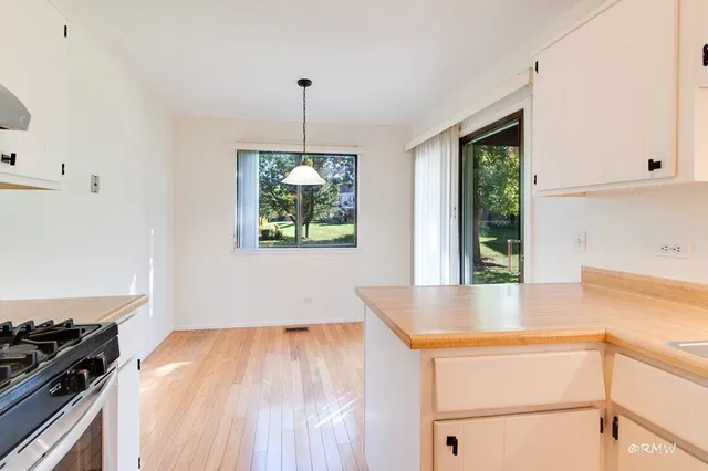 a kitchen with kitchen island a counter top space wooden floor and stainless steel appliances