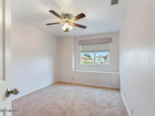 an empty room with windows and fan