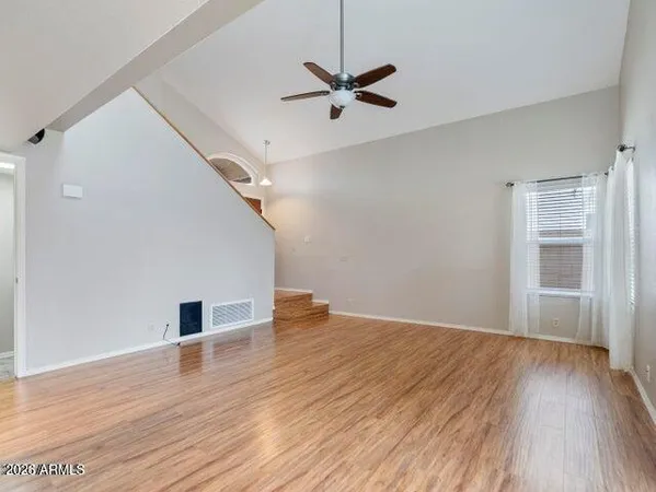 a view of empty room with wooden floor and ceiling fan