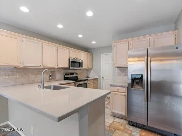 a kitchen with a refrigerator a sink a stove top oven a kitchen island with cabinets and wooden floor
