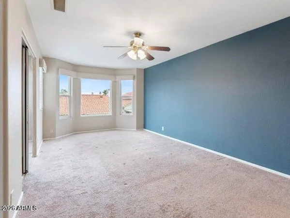 an empty room with windows and chandelier fan