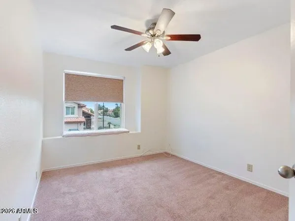 an empty room with a window and a fan