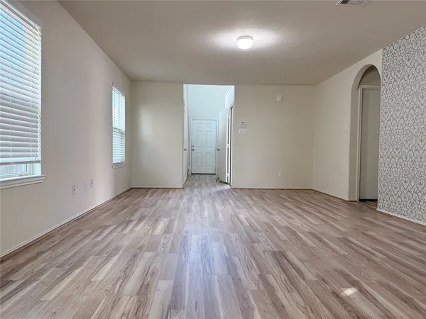 an empty room with wooden floor and windows