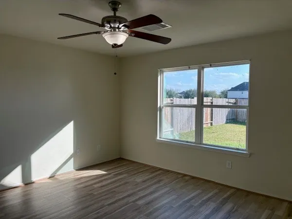 a view of an empty room with a window and wooden floor