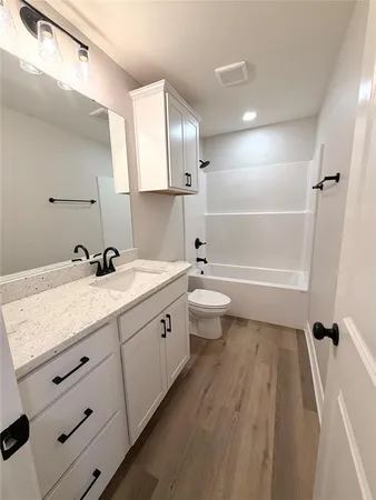 a bathroom with a granite countertop sink a toilet a mirror and shower