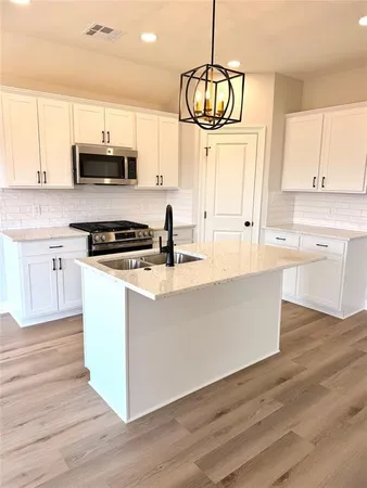 a kitchen with stainless steel appliances granite countertop a stove a sink and white cabinets