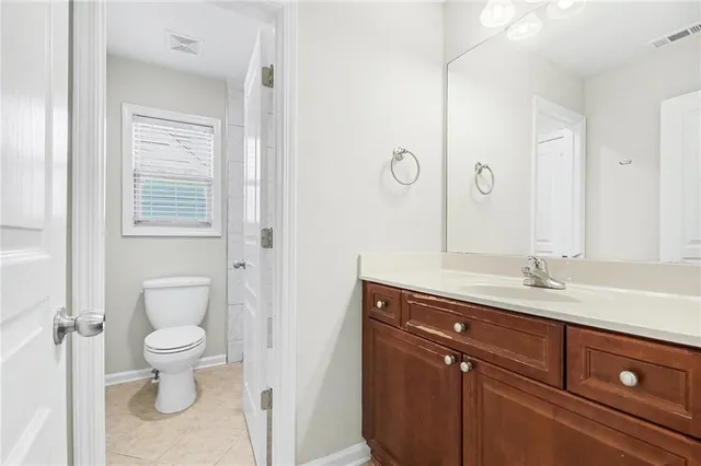 a bathroom with a granite countertop sink a toilet and a mirror