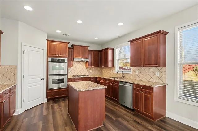 a kitchen with stainless steel appliances granite countertop a sink stove and refrigerator