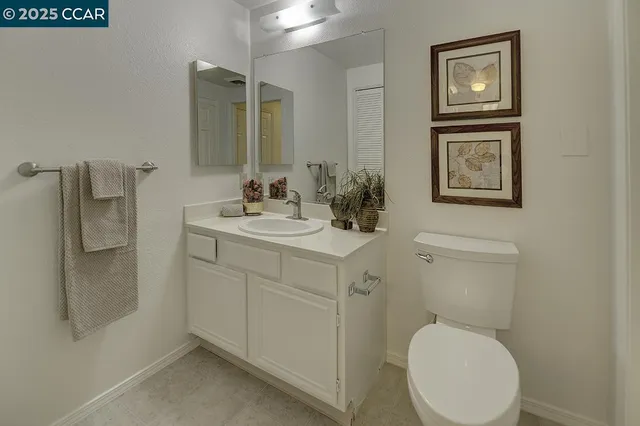 a bathroom with a toilet sink vanity and mirror