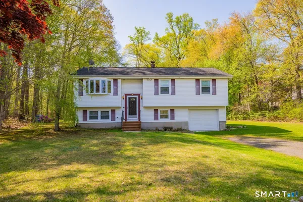 a view of a house with a big yard and large trees