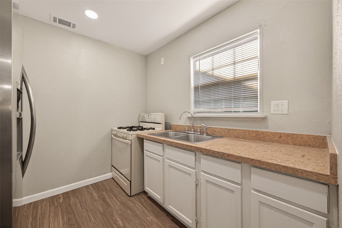 10141 Chadwick Street Houston, TX 77029 - Photo 9 of 25 a kitchen with stainless steel appliances granite countertop a sink a stove and a refrigerator with wooden floor