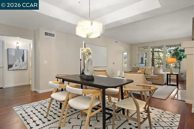 a living room with couches a fireplace and a dining table with wooden floor