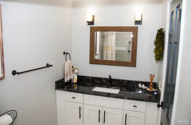 a bathroom with a granite countertop sink and a mirror