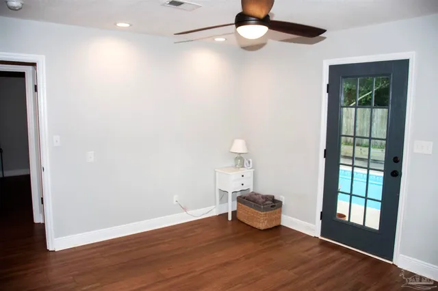 a view of an empty room with a window and wooden floor
