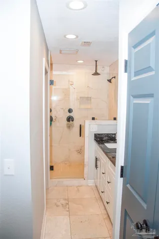 a bathroom with a granite countertop sink a mirror and a shower