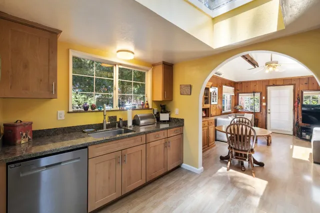 a kitchen with granite countertop a sink a window cabinets and dining table chair