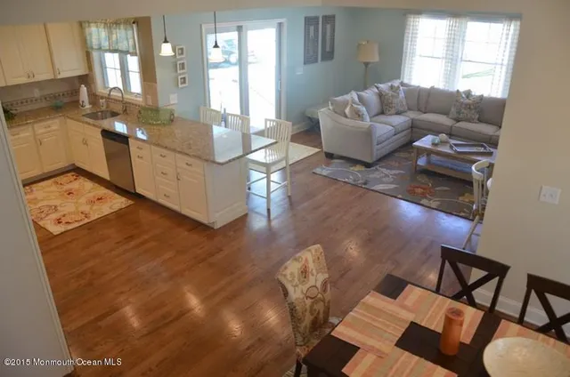 a view of a dining room and livingroom with furniture wooden floor a chandelier