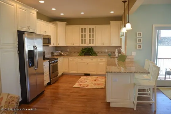 a kitchen with stainless steel appliances granite countertop a refrigerator a stove and a sink with wooden floor