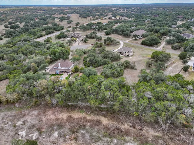 an aerial view of residential houses with outdoor space and trees