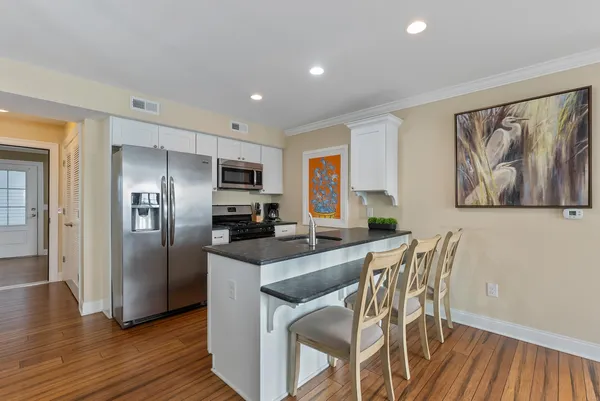 a kitchen with stainless steel appliances granite countertop a refrigerator a stove a sink and a dining table with wooden floor