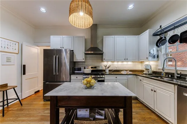 a kitchen with stainless steel appliances a stove a sink dishwasher and a refrigerator with wooden floor