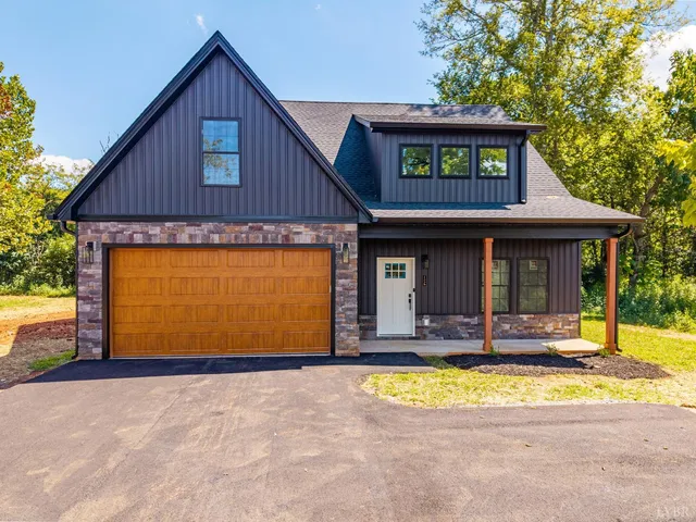 a view of a house with small yard plants and large tree