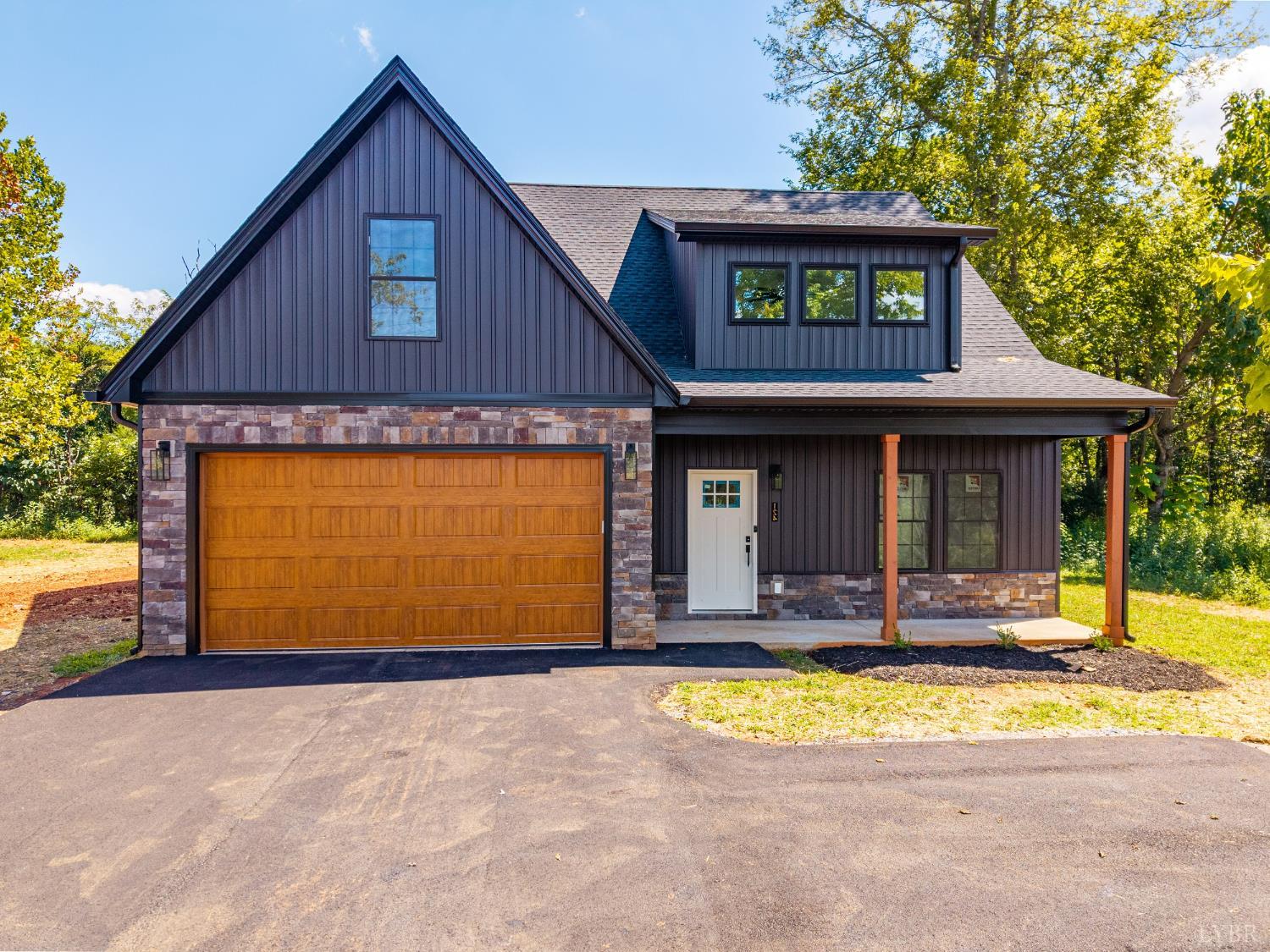 a view of a house with small yard plants and large tree