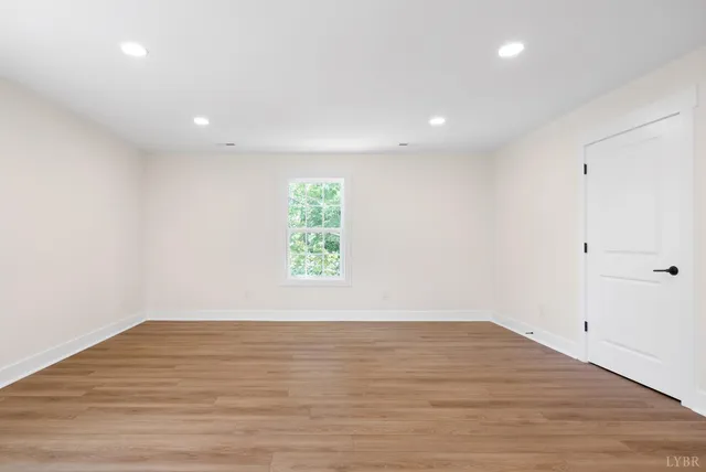 an empty room with wooden floor and window