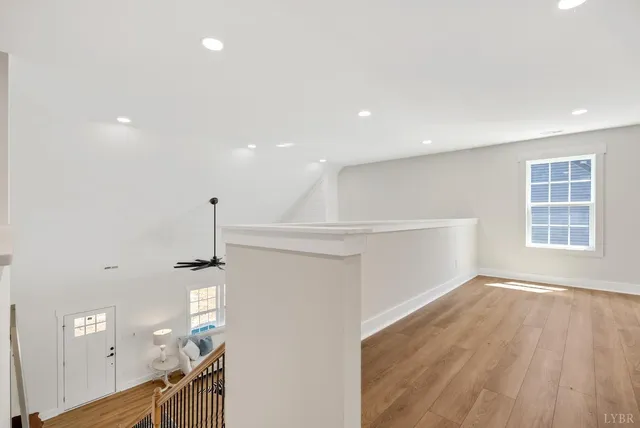 a view of empty room with wooden floor and fan