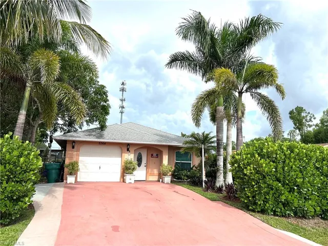 a front view of a house with a yard and palm trees