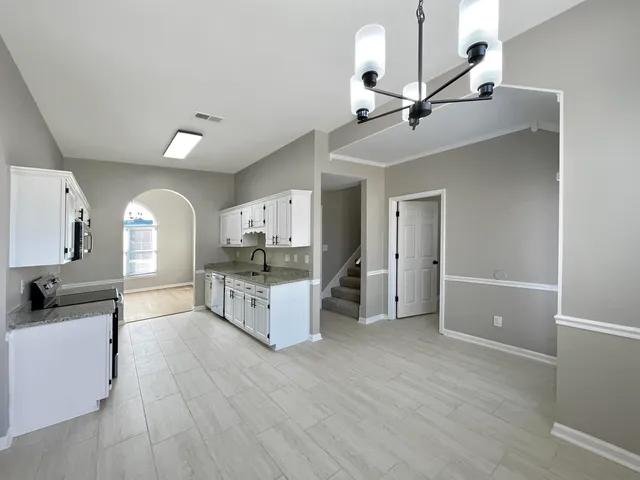an empty room with wooden floor a ceiling fan and windows