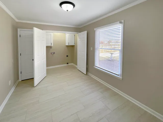 a view of an empty room with a window and wooden floor