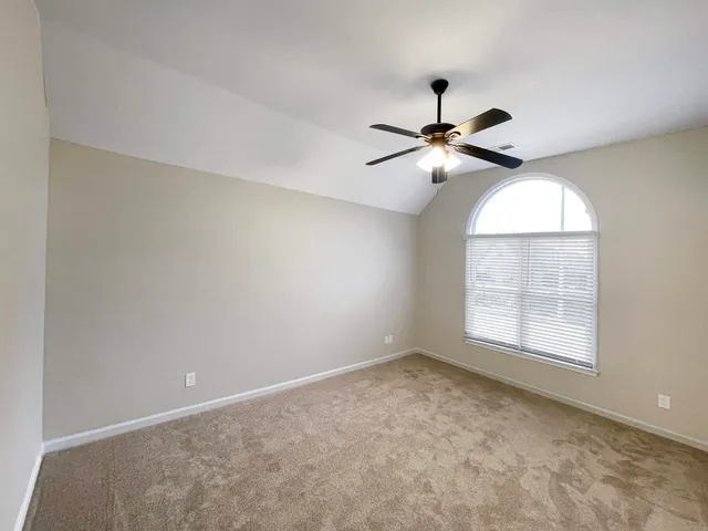 an empty room with windows and fan