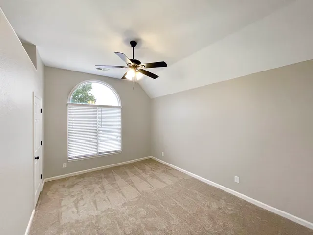 an empty room with windows and fan