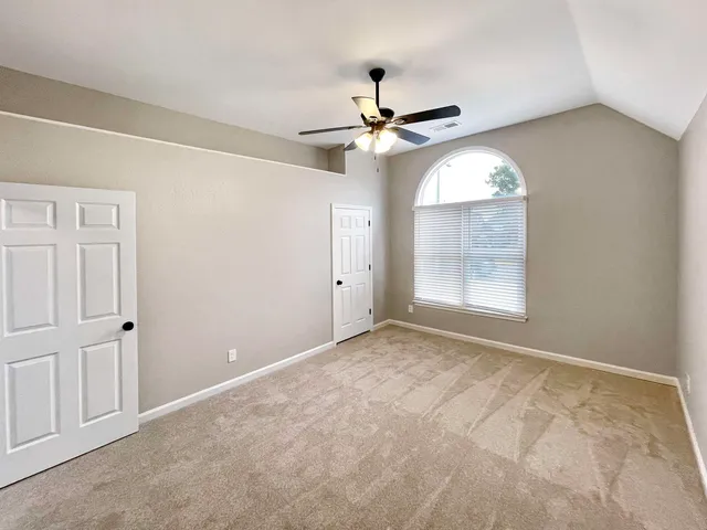 an empty room with windows and fan