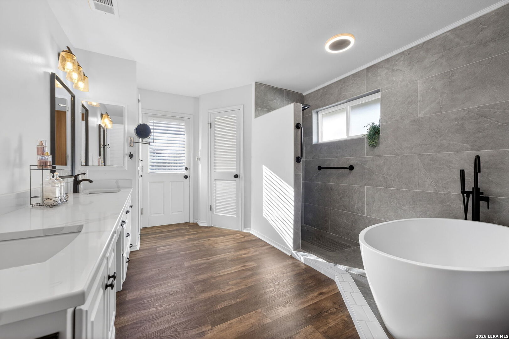 a bathroom with a tub a sink a window and a mirror