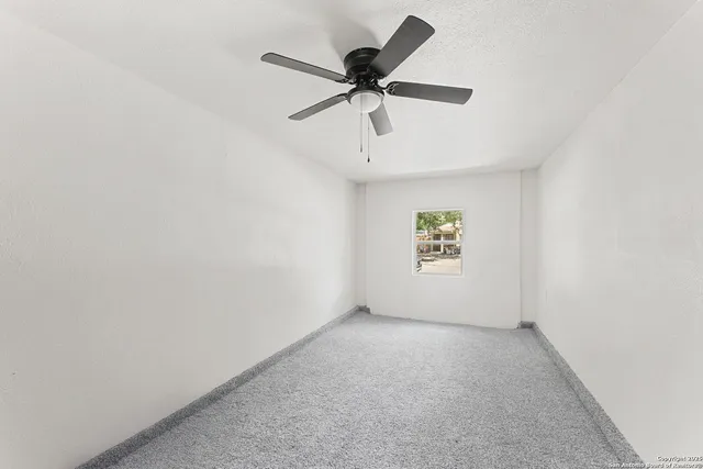 an empty room with a window and a fan