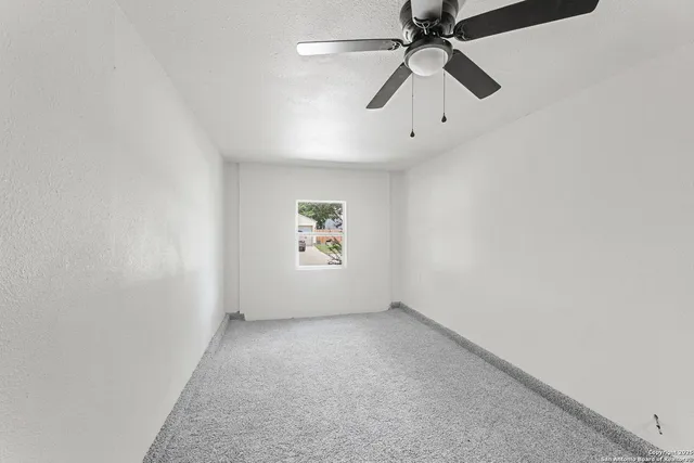 an empty room with chandelier fan