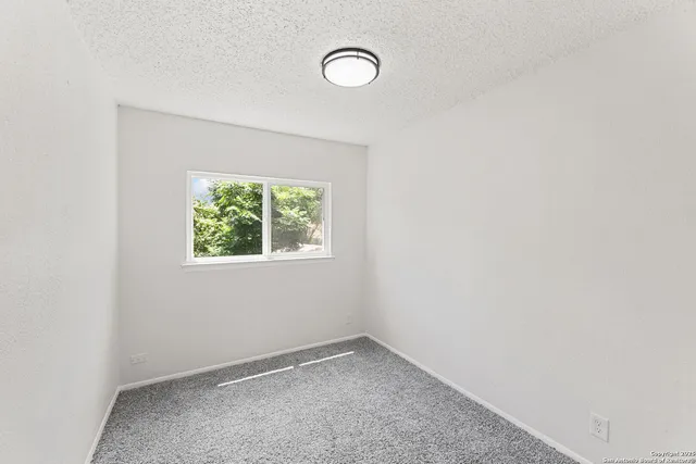 an empty room with a window and a fan