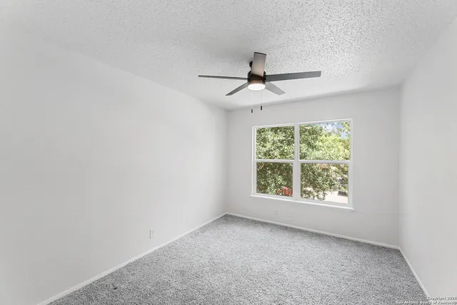 an empty room with a window and a ceiling fan
