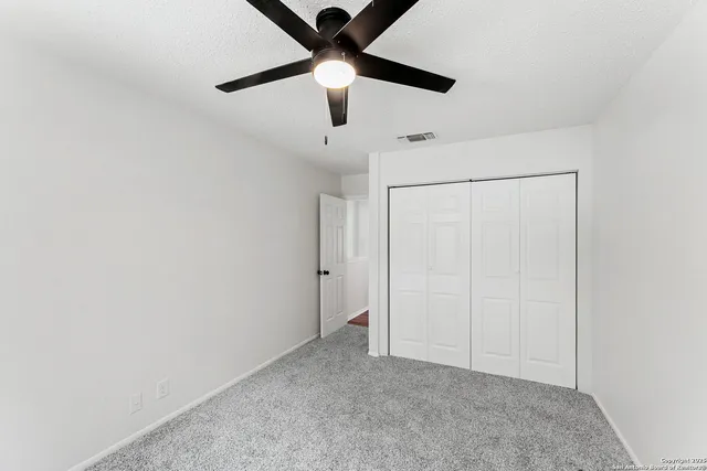an empty room with a ceiling fan and carpet