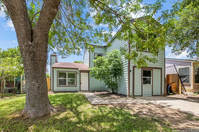 a view of a house with a tree in front of it