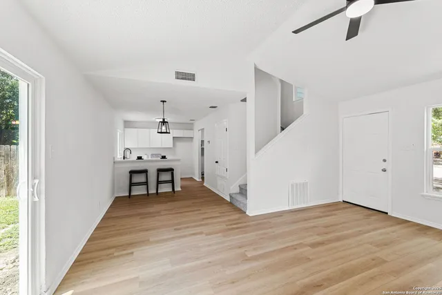 a big room with wooden floor fireplace and windows