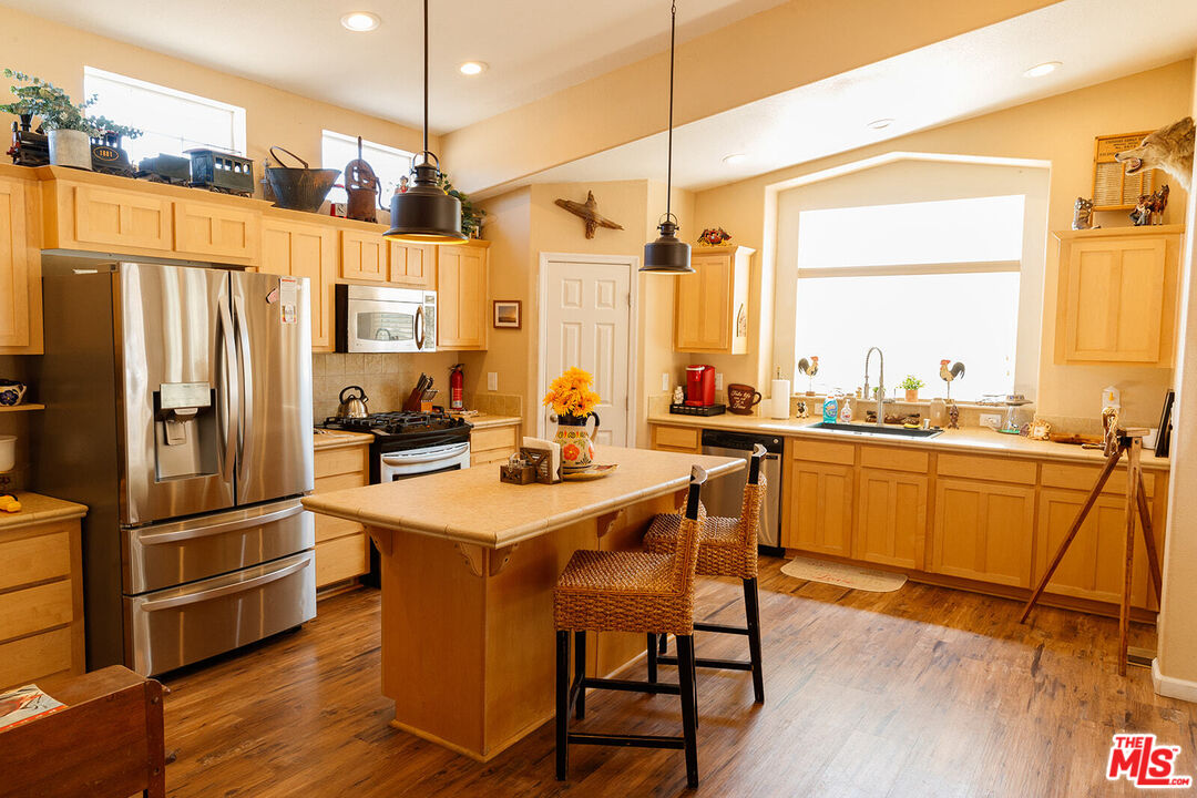55626 Pipes Canyon Road Yucca Valley, CA 92284 - Photo 6 of 61 a kitchen with a table chairs refrigerator and window